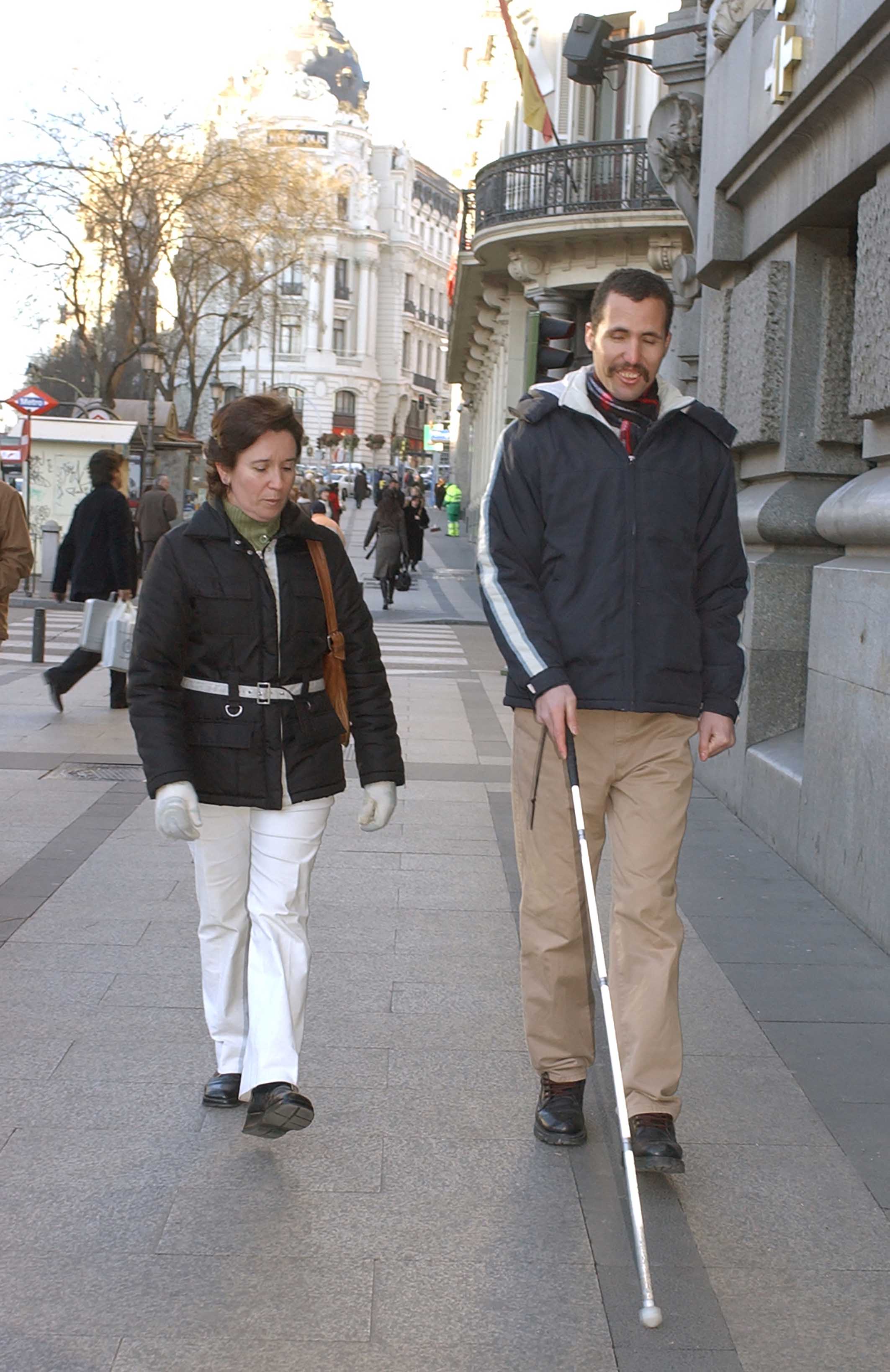 Una técnico de rehabilitación enseña movilidad a una persona ciega extranjera