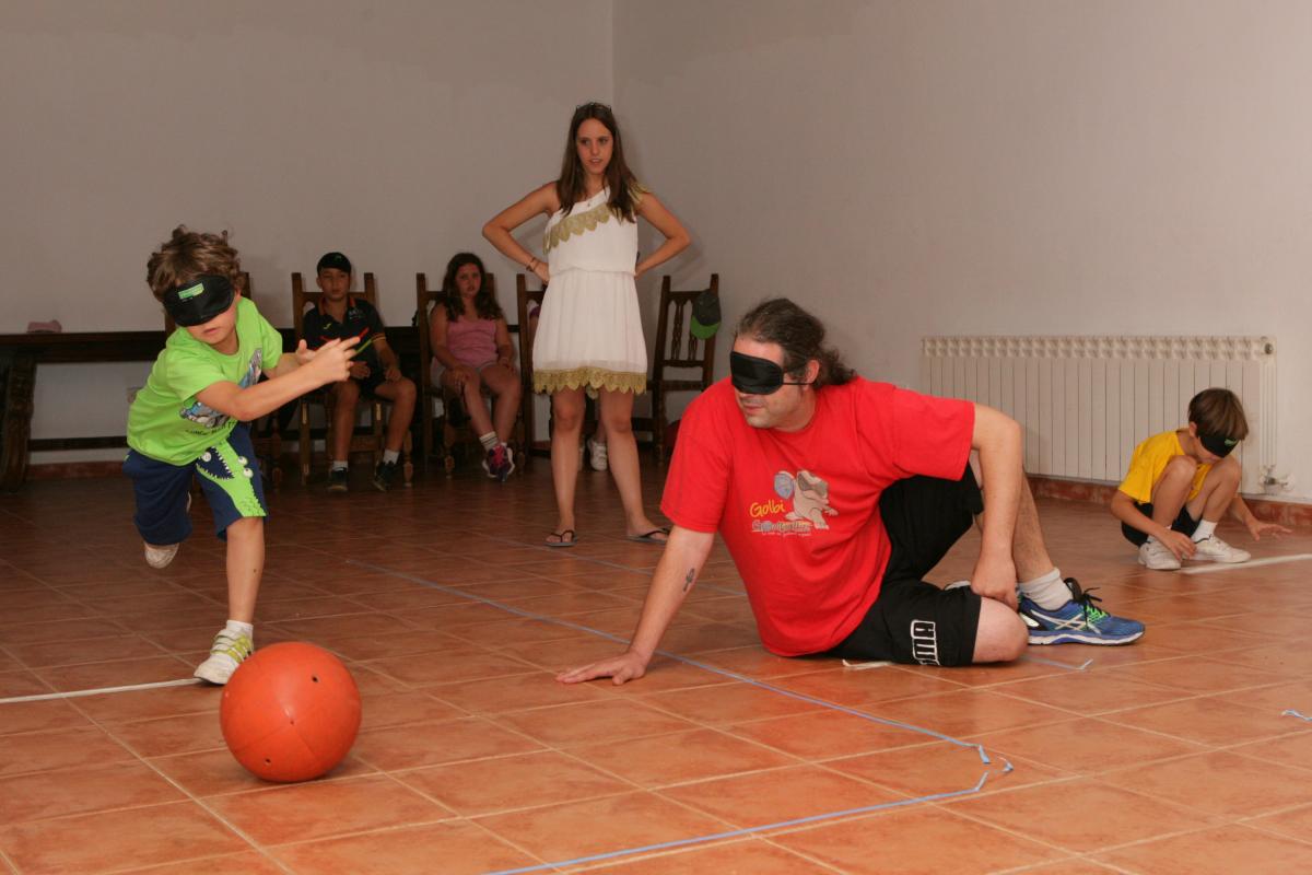 Un niño del campamento practica Goalball junto al jugador Tomás Rubio