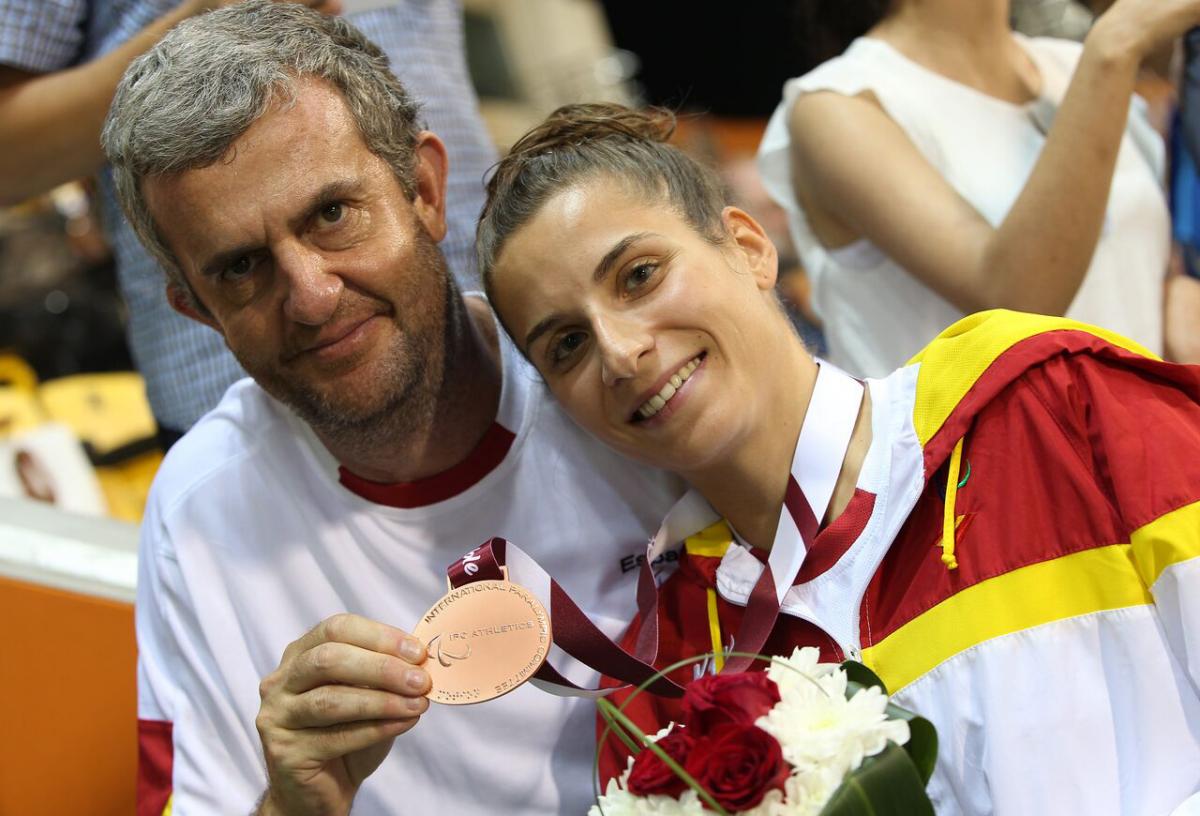 Sara Martínez junto a su entrenador muestran una medalla conseguida por la atleta
