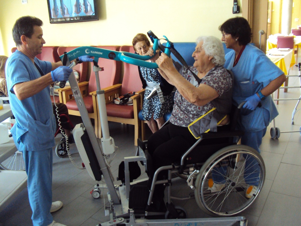 Una usuaria utiliza un aparato de rehabilitación ayudado por los técnicos