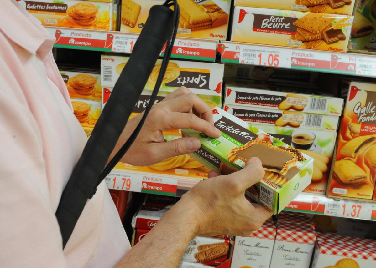 Una persona ciega lee la etiqueta en braille de un producto de consumo