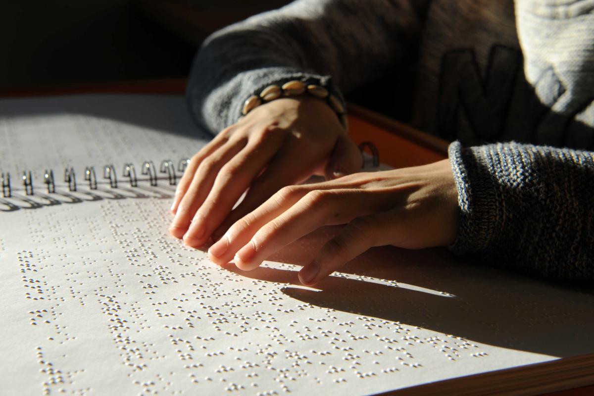 Primer plano de unas manos leyendo braille