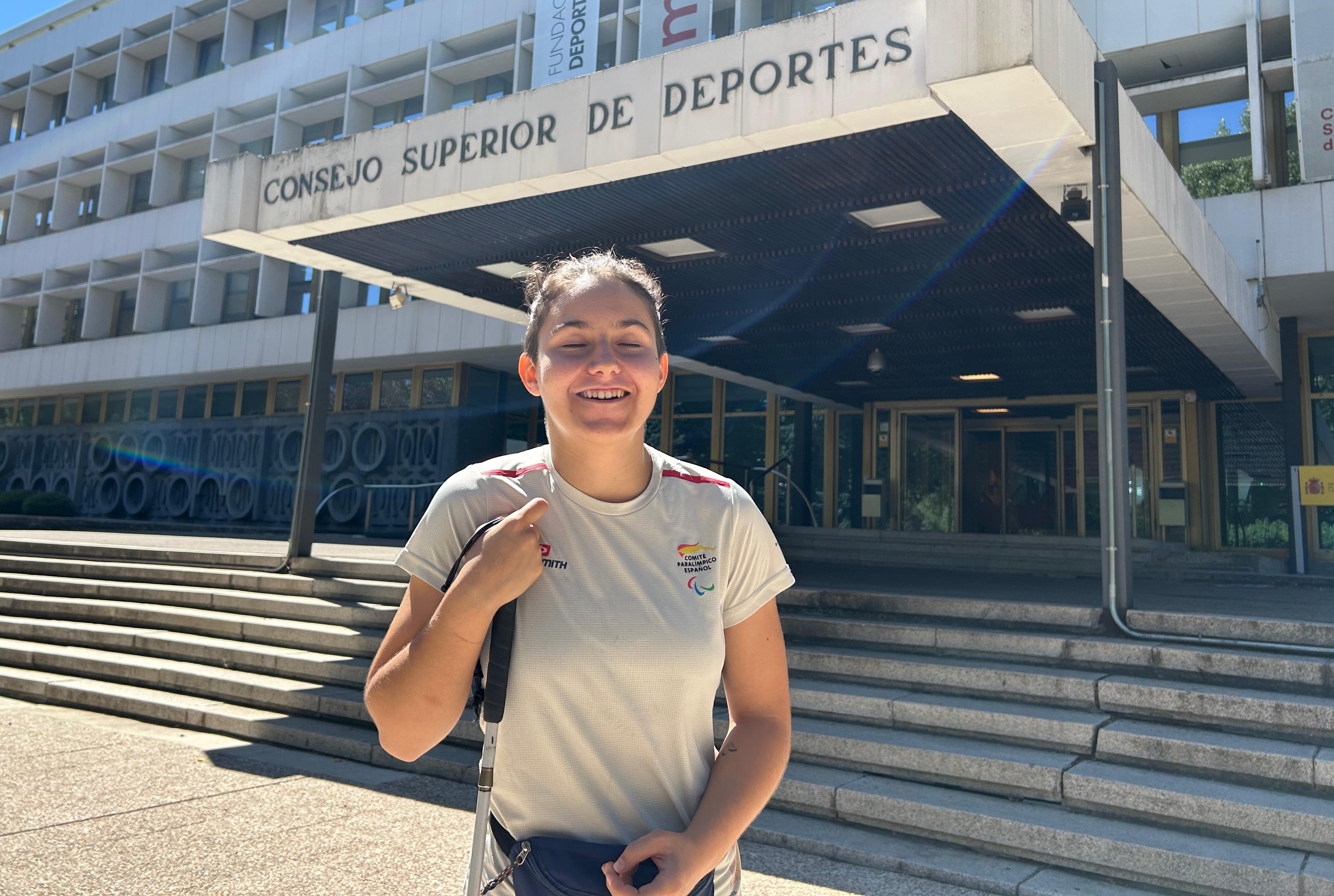 La judoca paralímpica María Manzanero posa sonriente, con su bastón blanco en mano, delante de la escalinata del Consejo Superior de Deportes