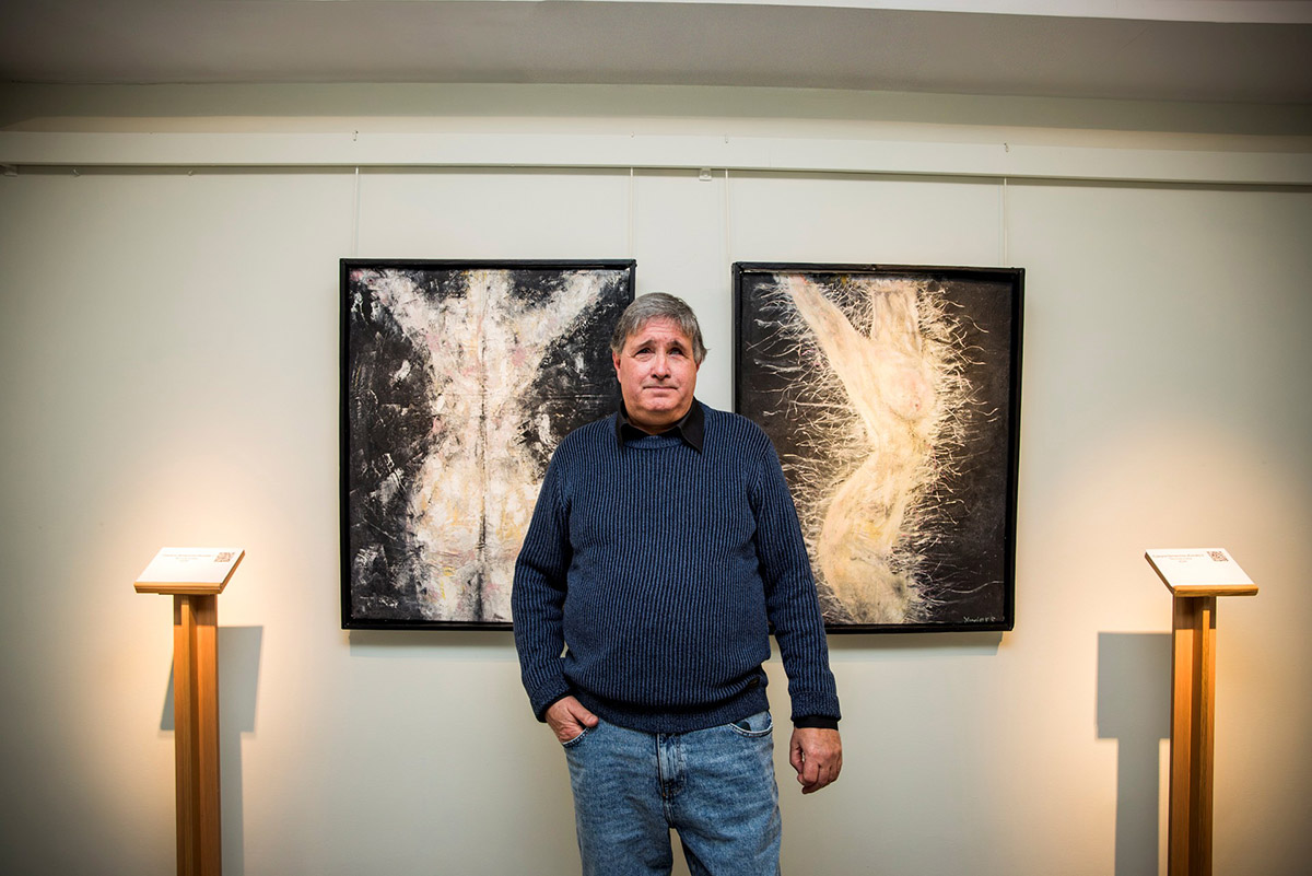 XavierE posa entre dos de las obras expuestas