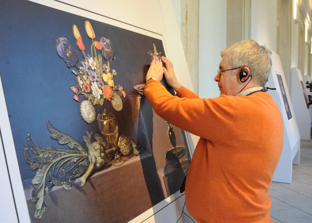 Un afiliado tocando los detales de Bodegón con alcachofas, flores y recipientes de vidrio 