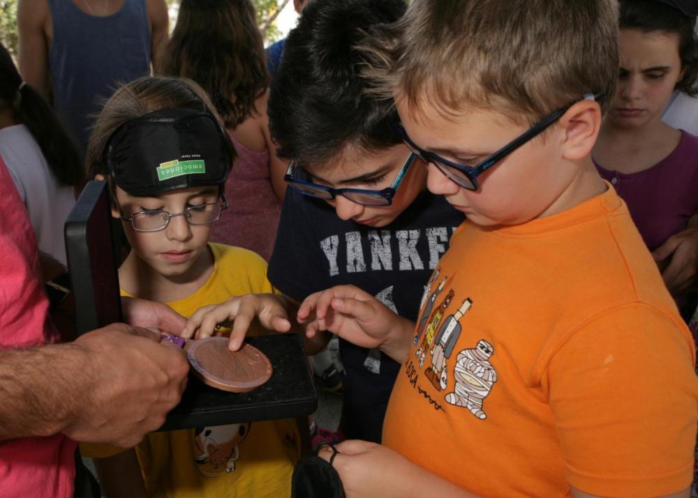 Algunos de los niños participantes tocan la medalla de uno de los deportistas paralímpicos