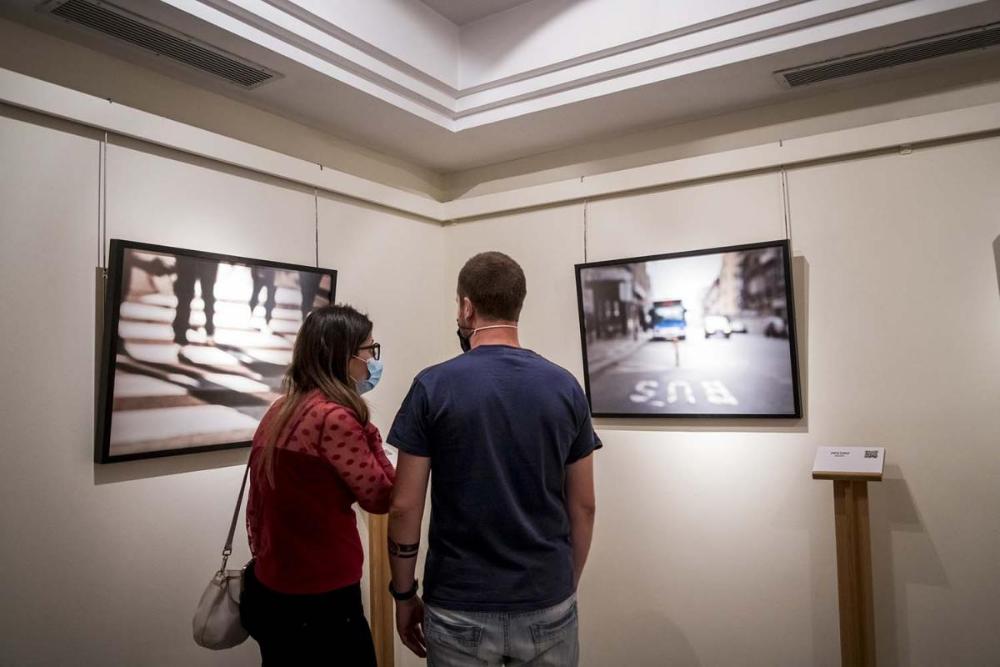 Dos personas observan las fotografías de Victoria Adame