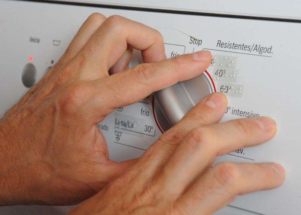 Imagen de unas manos leyendo el braille incluido en una lavadora