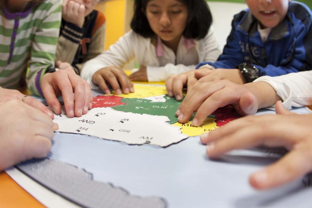 Varios niños utilizando mapas en relieve