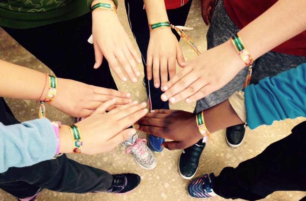 Alumnos participantes en el concurso muestran sus manos con las pulseras del Concurso
