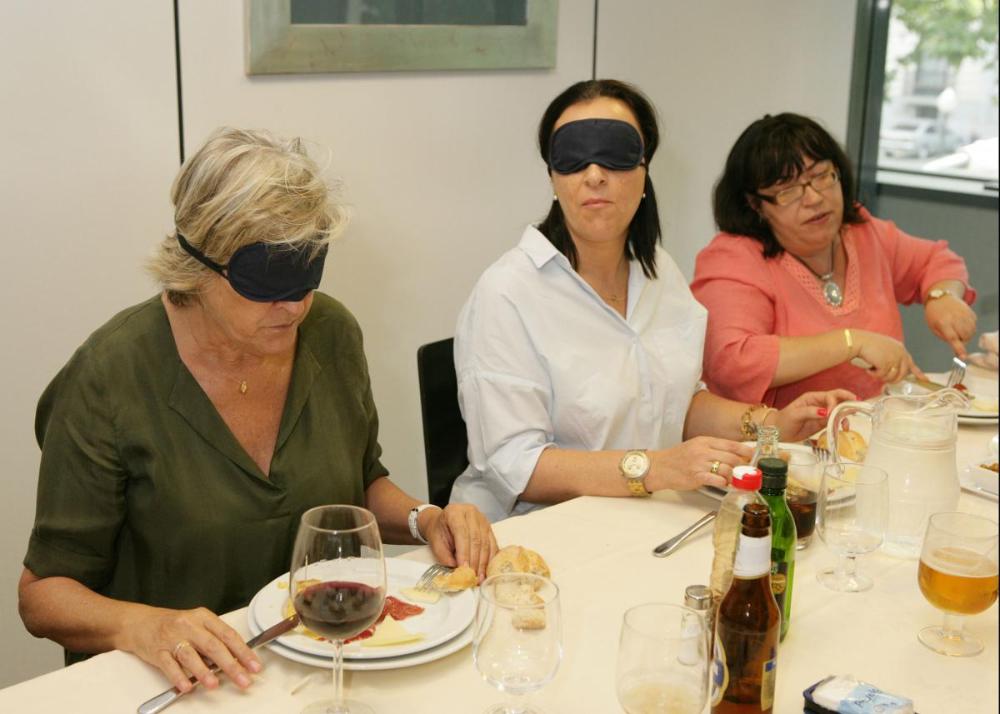 Dos de las participantes tratan de comer con el antifaz