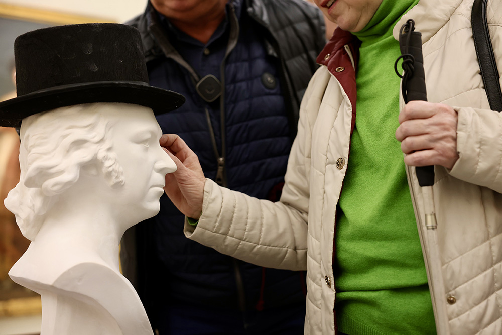 Dos personas ciegas tocan el busto de Goya