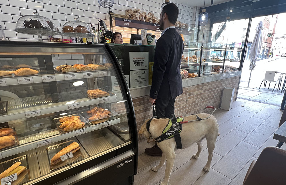 Un usuario con su perro guía en una cafetería