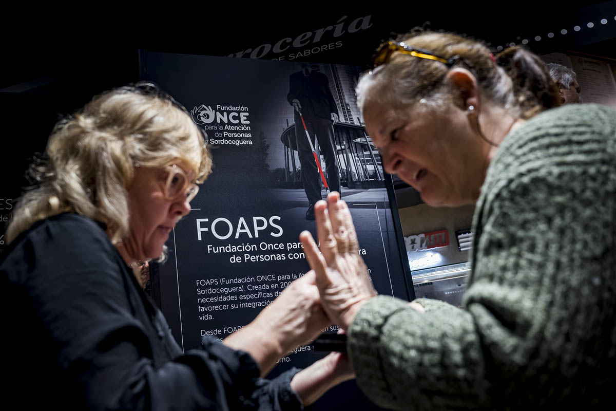 Una mujer con sordoceguera junto a su guía intérprete durante la presentación