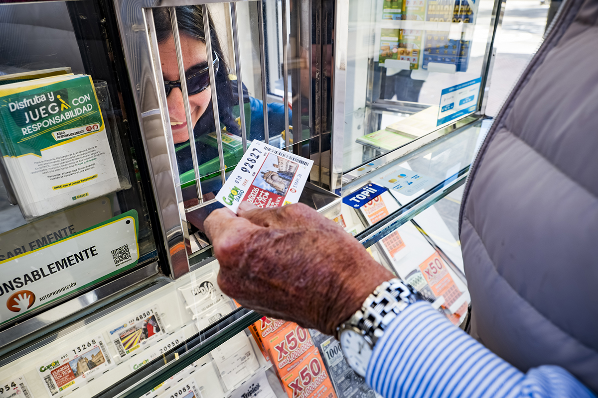 Una vendedora de la ONCE atiende a un cliente desde su quiosco
